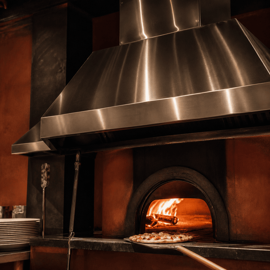 Wood-fired pizza oven hood glowing in an artisan pizzeria
